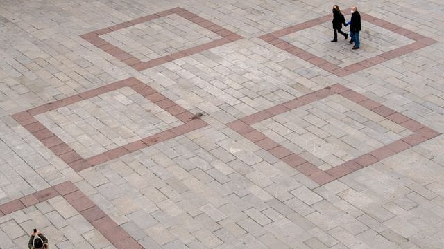 Passanten laufen über den fast leeren Marienplatz vor dem Rathaus in der Innenstadt von München. Passanten laufen über den fast leeren Marienplatz vor dem Rathaus in der Innenstadt von München.