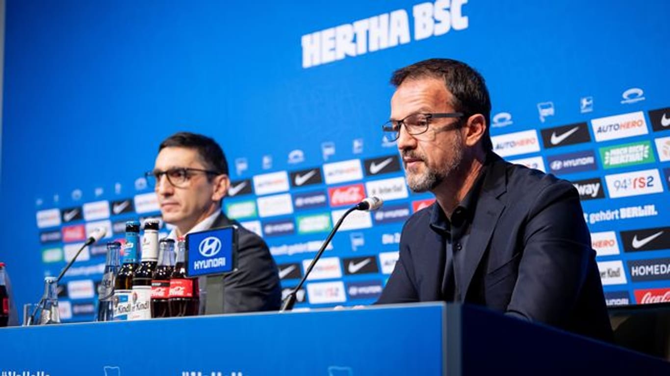 Trainer Tayfun Korkut (l) und Fredi Bobic, Geschäftsführer von Hertha BSC, sitzen während einer Pressekonferenz auf dem Podium.