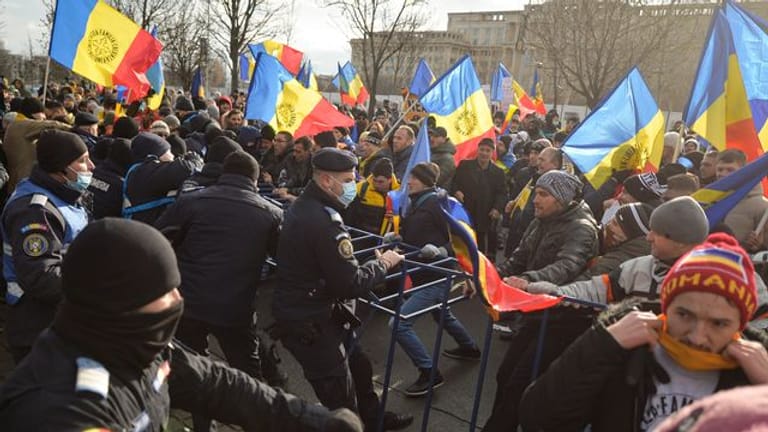 Polizisten der Bereitschaftspolizei ringen vor dem Parlamentspalast in Bukarest mit Demonstranten.