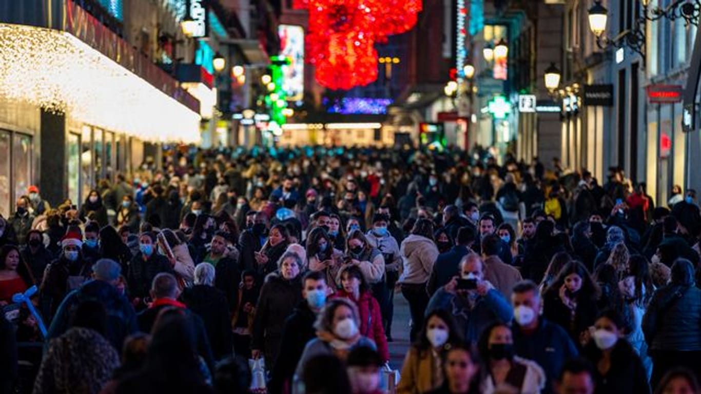 Menschen tragen Schutzmasken gehen durch die Innenstadt in Madrid.