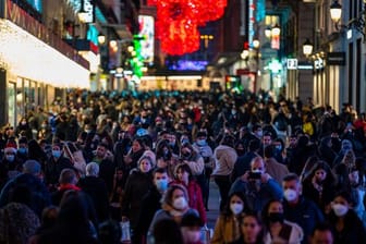 Menschen tragen Schutzmasken gehen durch die Innenstadt in Madrid.