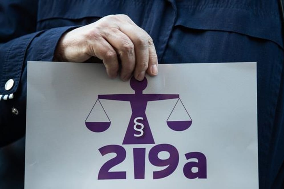 Eine Frau hält bei einer Kundgebung einen Zettel mit der Aufschrift "219a nicht zeitgemäß!".