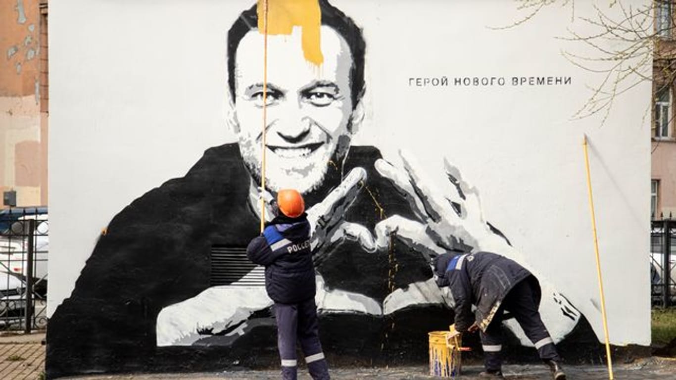Städtische Arbeiter übermalen ein Graffiti mit dem Konterfei von Alexej Nawalny.