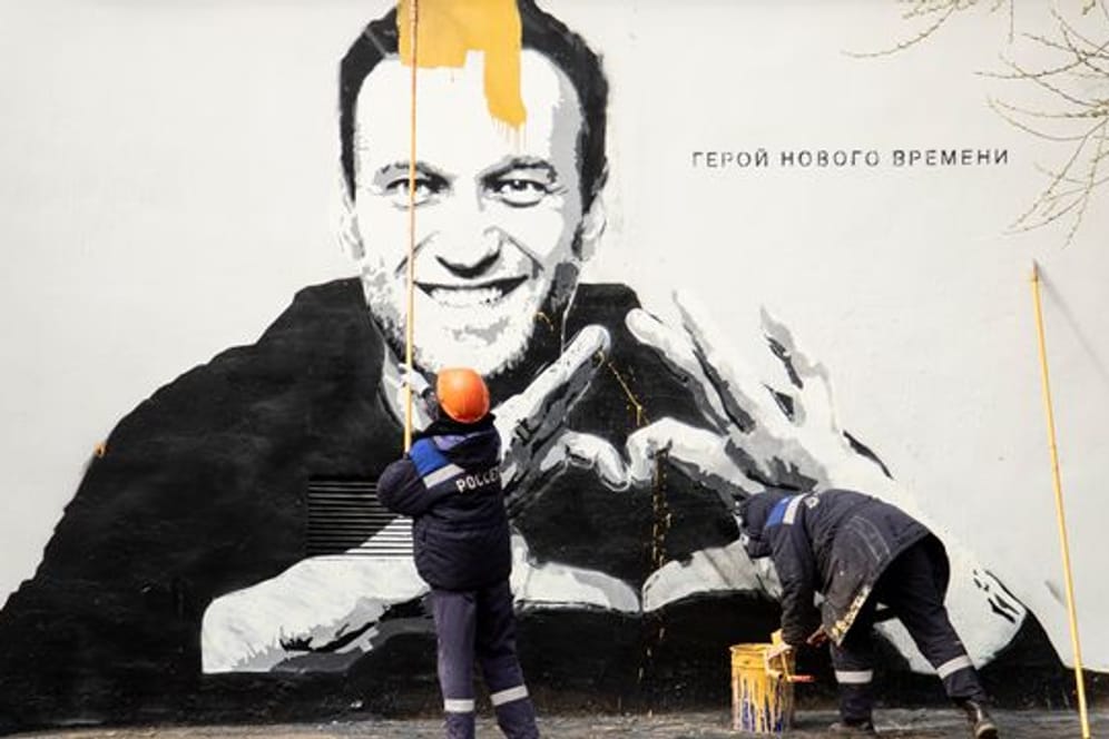 Städtische Arbeiter übermalen ein Graffiti mit dem Konterfei von Alexej Nawalny.