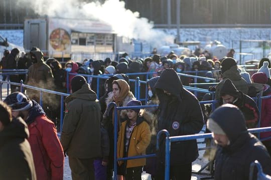 Migranten stehen in der Nähe eines Logistikzentrums an der polnisch-belarussischen Grenze an einer Essensausgabe an.