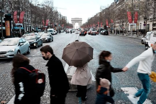 Menschen überqueren die Avenue des Champs-Élysées in Paris.