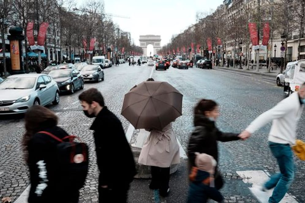 Menschen überqueren die Avenue des Champs-Élysées in Paris.