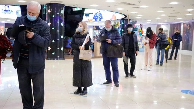 Menschen stehen in einem Einkaufszentrum in Moskau für eine Corona-Impfung an.