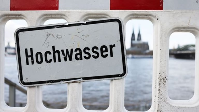 Ein Warnschild mit der Aufschrift "Hochwasser" steht am Rheinufer (Symbolbild): Am Donnerstag hatte der Rhein die erste Hochwassermarke überschritten.