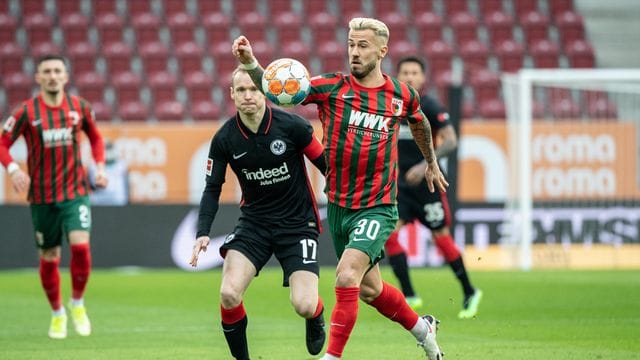 Augsburgs Niklas Dorsch (v) versucht, den Ball gegen Eintrachts Kapitän Sebastian Rode zu behaupten. Augsburgs Niklas Dorsch (v) versucht, den Ball gegen Eintrachts Kapitän Sebastian Rode zu behaupten.