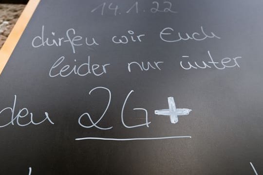 Auf einem Schild wird vor einem Cafe auf die 2G-plus-Regel hingewiesen.