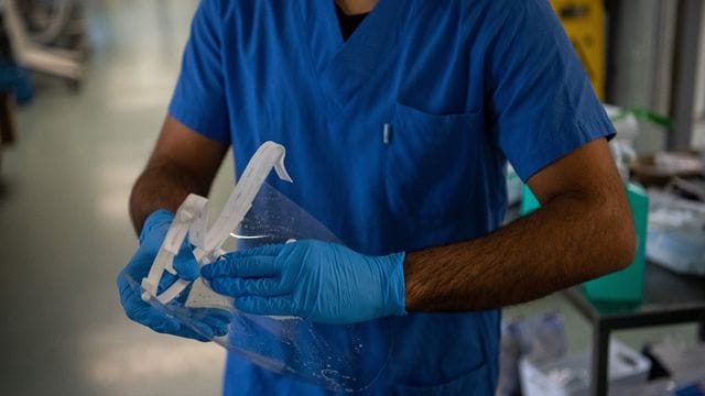 Ein Pfleger desinfiziert auf einer Covid-Intensivstation sein Visier. Ein Pfleger desinfiziert auf einer Covid-Intensivstation sein Visier.
