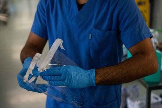 Ein Pfleger desinfiziert auf einer Covid-Intensivstation sein Visier.