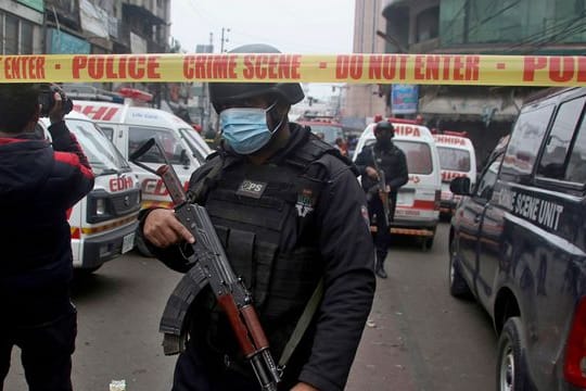 Polizisten stehen am Anschlagsort in Lahore, während Krankenwagen darauf warten Verletzte abzutransportieren.