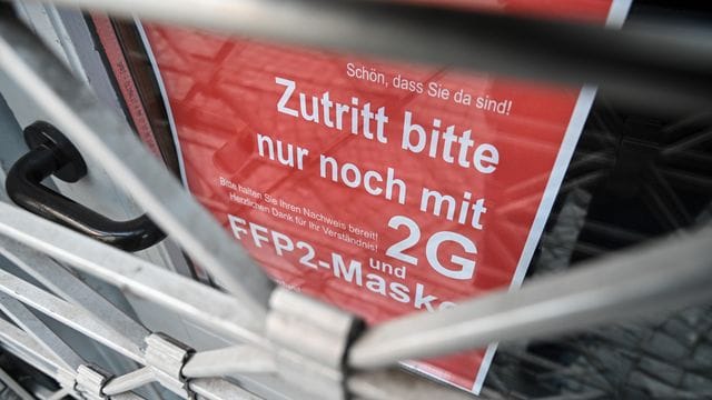 Ein Schild weist am Eingang eines Ladens in der Innenstadt auf die Maskenpflicht und die 2G-Regel hin. Ein Schild weist am Eingang eines Ladens in der Innenstadt auf die Maskenpflicht und die 2G-Regel hin.