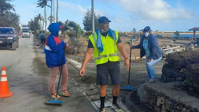 Anwohner fegen Asche von einer Straße nach dem Ausbruch eines unterseeischen Vulkans vor Tonga. Anwohner fegen Asche von einer Straße nach dem Ausbruch eines unterseeischen Vulkans vor Tonga.