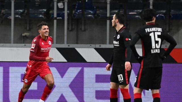 Bielefelds Alessandro Schöpf (l) feiert sein Tor zur 2:0-Führung neben den Frankfurtern Filip Kostic (M) und Daichi Kamada.