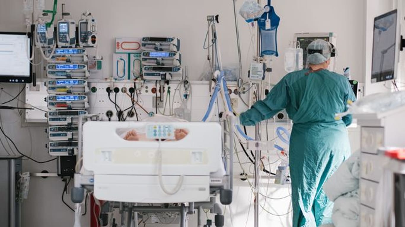 Eine Intensivpflegerin versorgt auf der Intensivstation einen an Covid-19 erkrankten Patienten.