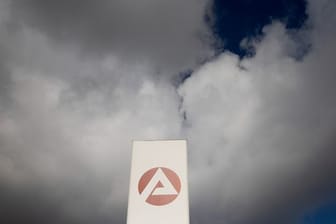 Wolken ziehen über ein Schild der Agentur für Arbeit