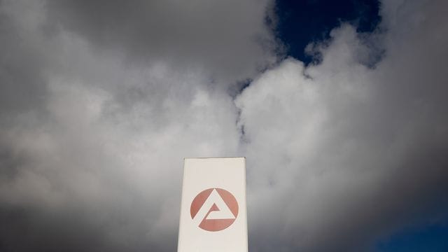 Wolken ziehen über ein Schild der Agentur für Arbeit