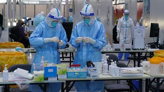 PCR-Prüfer in Schutzanzügen arbeiten in einem Prüfzentrum auf dem Flughafen von Peking. PCR-Prüfer in Schutzanzügen arbeiten in einem Prüfzentrum auf dem Flughafen von Peking.