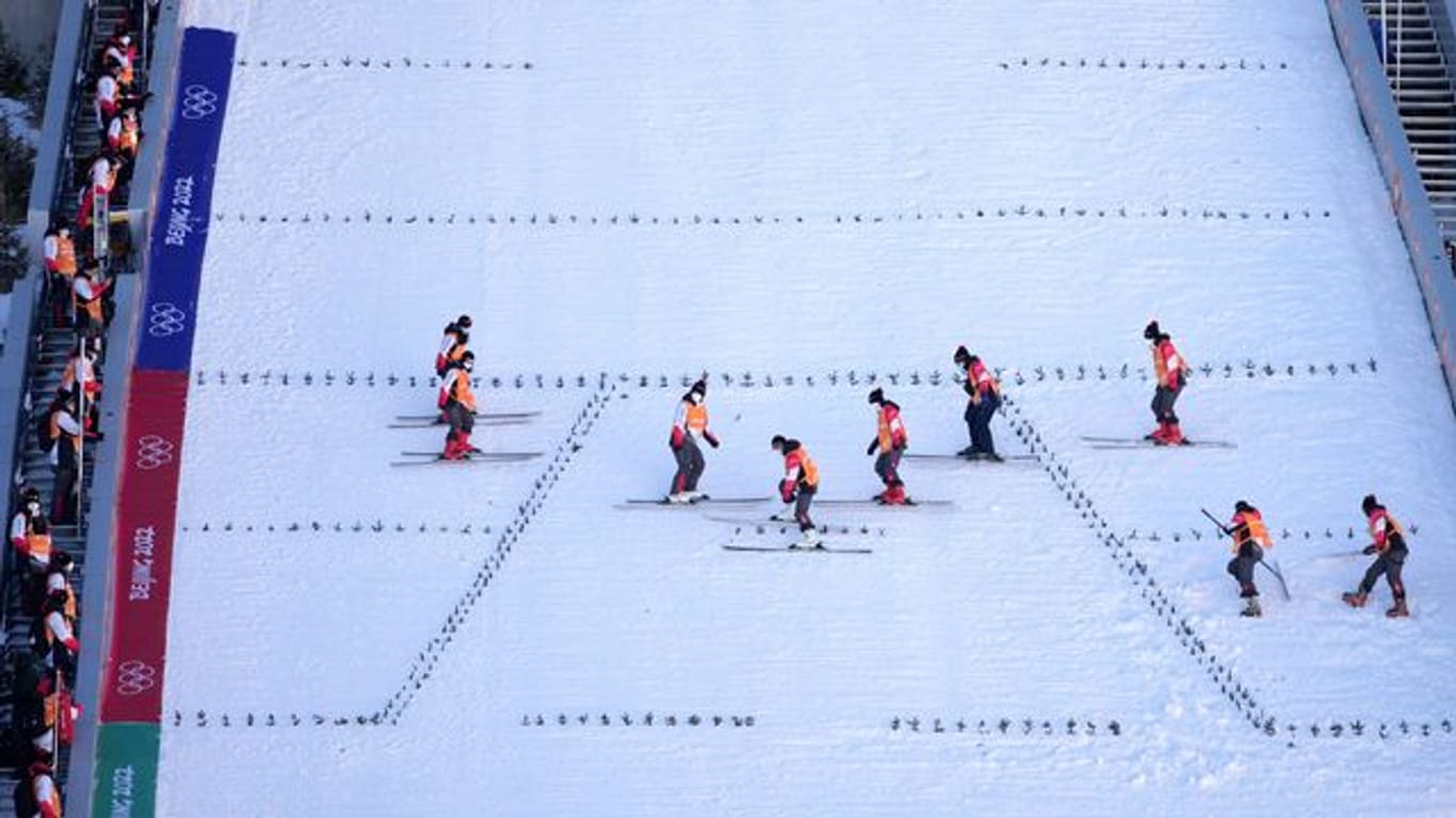 Mitarbeiter bereiten die Skisprungschanze vor.