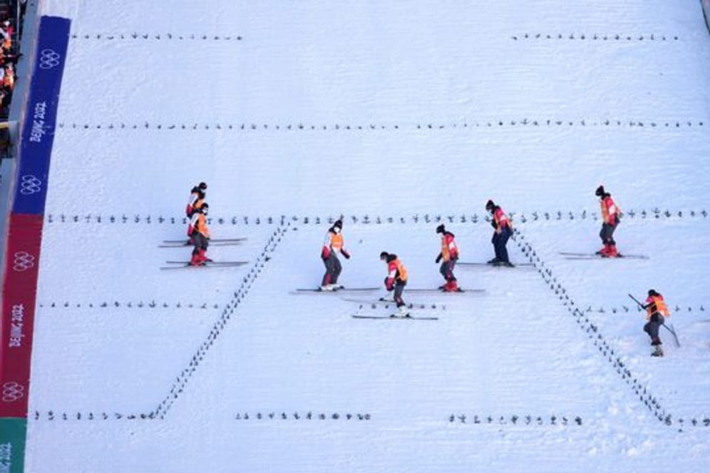 Mitarbeiter bereiten die Skisprungschanze vor.