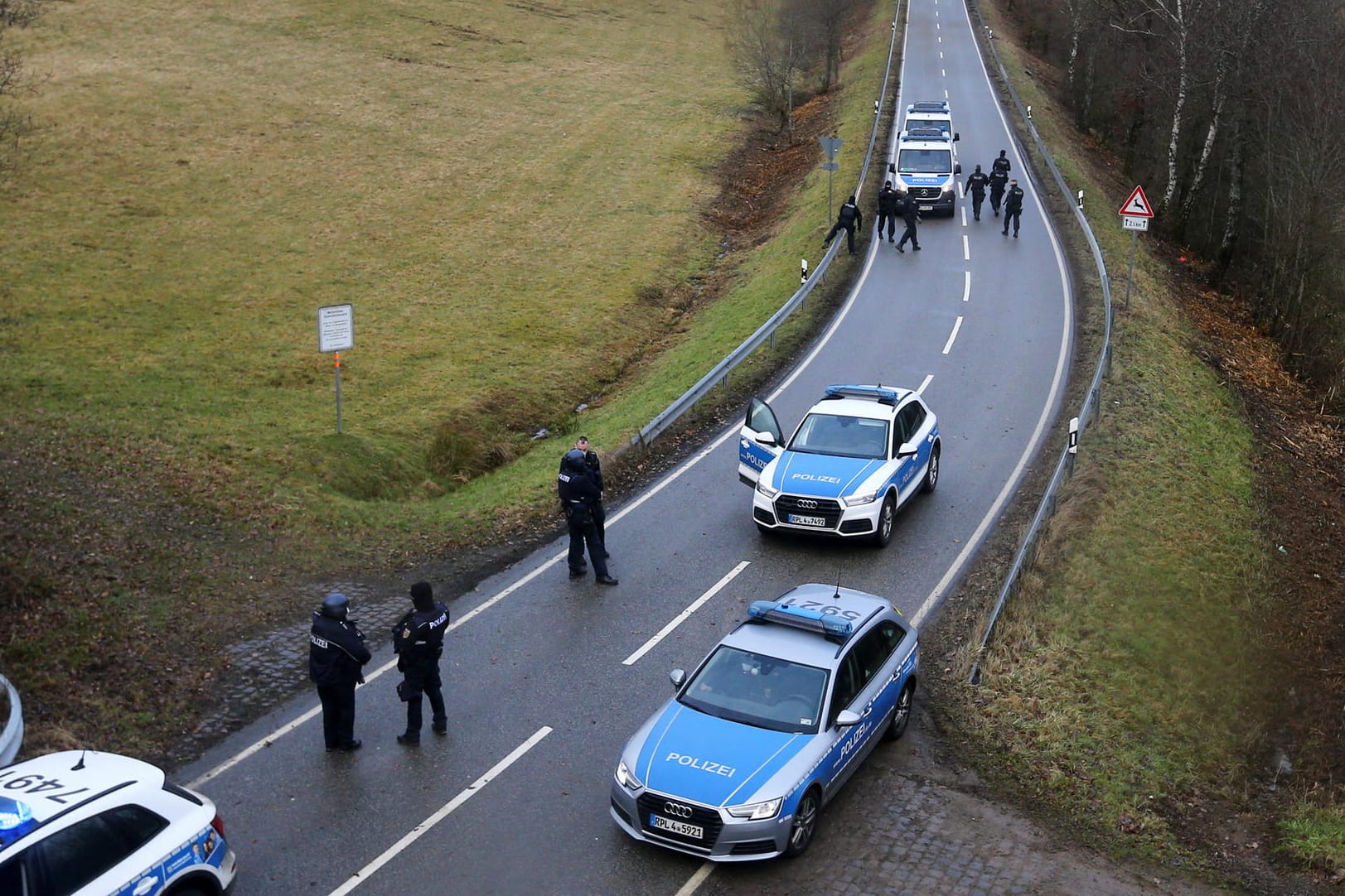 Polizisten durchsuchen die Gegend in der Nähe des Tatorts: Die Trauer um die bei Kusel getöteten Beamten ist groß.