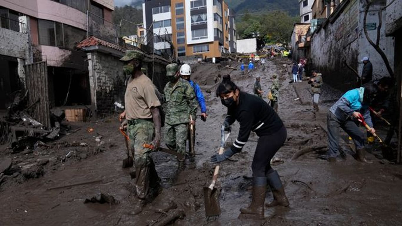 Anwohner und Soldaten arbeiten daran, die Straßen in der Hauptstadt Quito von Schlamm zu befreien.