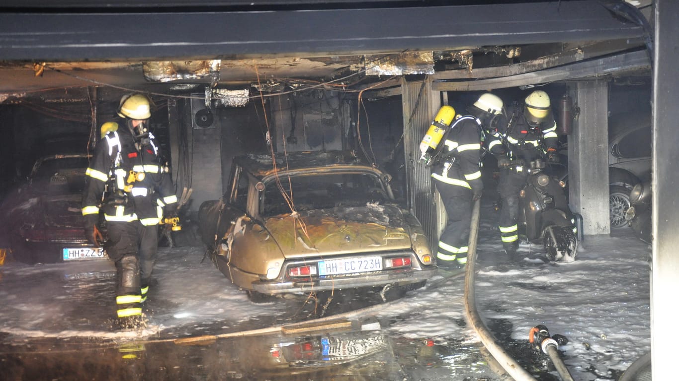 Feuerwehrleute stehen in der Tiefgarage: Mehrere Autos sind dem Feuer zum Opfer gefallen.