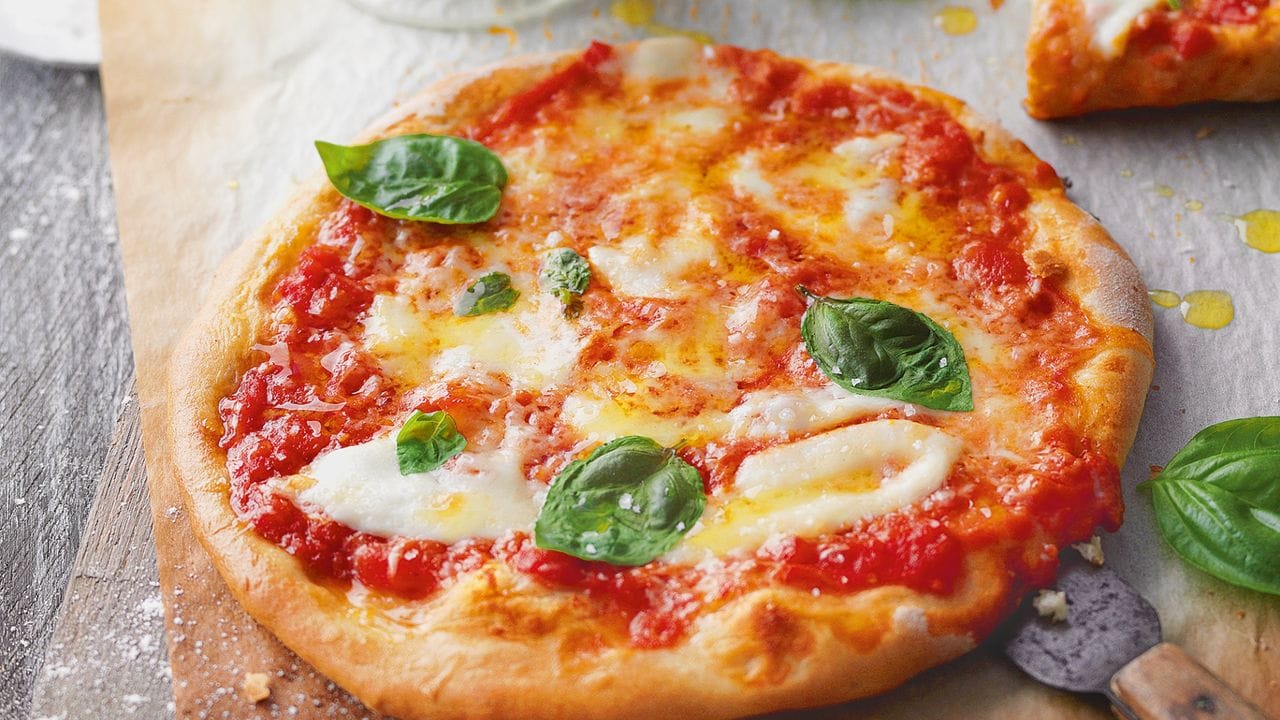 Die Pizza Margherita mit Basilikum, Mozzarella und Parmesan kommt nicht ohne Tomatensauce.