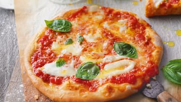 Die Pizza Margherita mit Basilikum, Mozzarella und Parmesan kommt nicht ohne Tomatensauce.