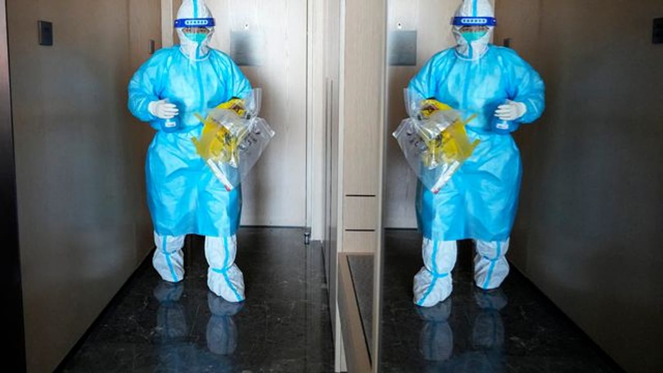 Ein medizinischer Mitarbeiter betritt ein Hotelzimmer, um einen COVID-19-Test zu machen.