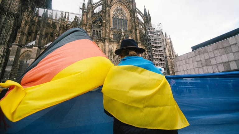 Frau mit Ukraine- und Deutschlandflagge: Die Menschen in West- und Ostdeutschland bewerten die Lage in der Ukraine teils sehr unterschiedlich.