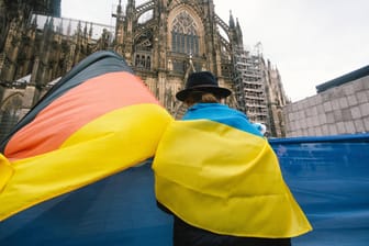 Frau mit Ukraine- und Deutschlandflagge: Die Menschen in West- und Ostdeutschland bewerten die Lage in der Ukraine teils sehr unterschiedlich.
