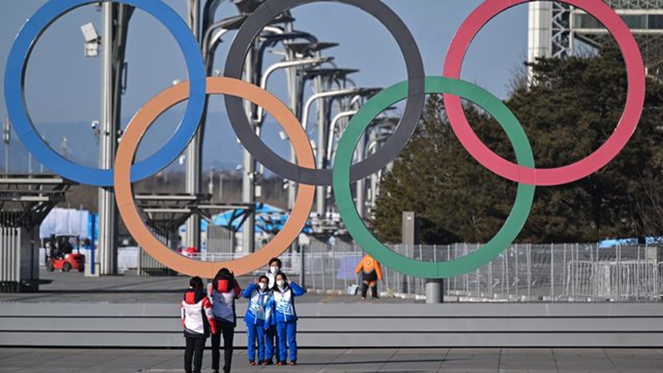 Von Olympia-Stimmung ist in Peking wenig zu spüren: Volunteers stehen vor den olympischen Ringen für ein Selfie.