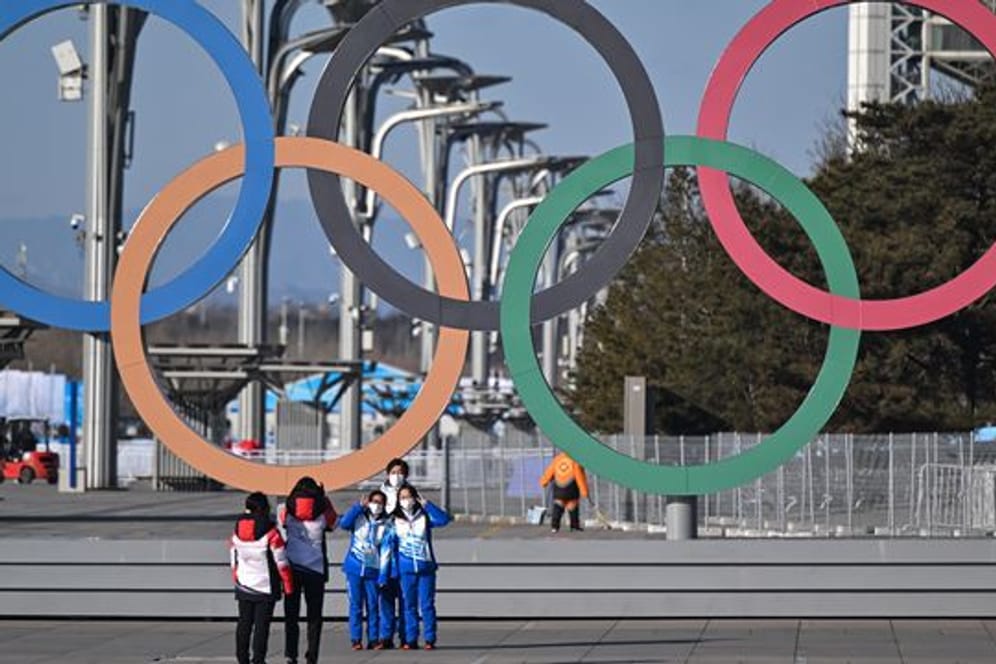 Von Olympia-Stimmung ist in Peking wenig zu spüren: Volunteers stehen vor den olympischen Ringen für ein Selfie.