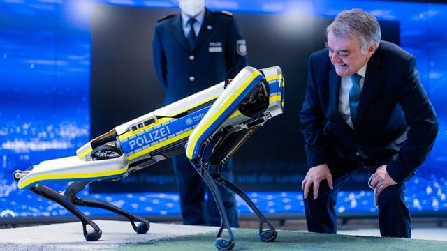 Herbert Reul, Innenminister von Nordrhein-Westfalen, mit einem Roboter-Hund (Archivbild): Er setzt auf die Maschinen als Helfer für Beamte.