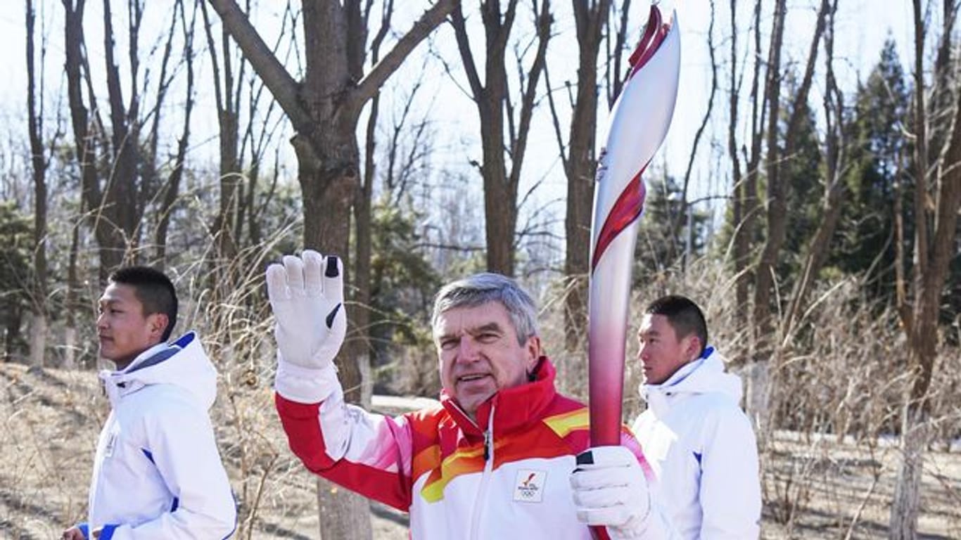 Thomas Bach (M), Präsident des Internationalen Olympischen Komitees (IOC), nimmt am olympischen Fackellauf teil.