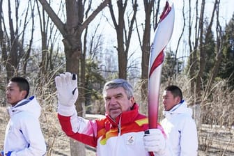 Thomas Bach (M), Präsident des Internationalen Olympischen Komitees (IOC), nimmt am olympischen Fackellauf teil.