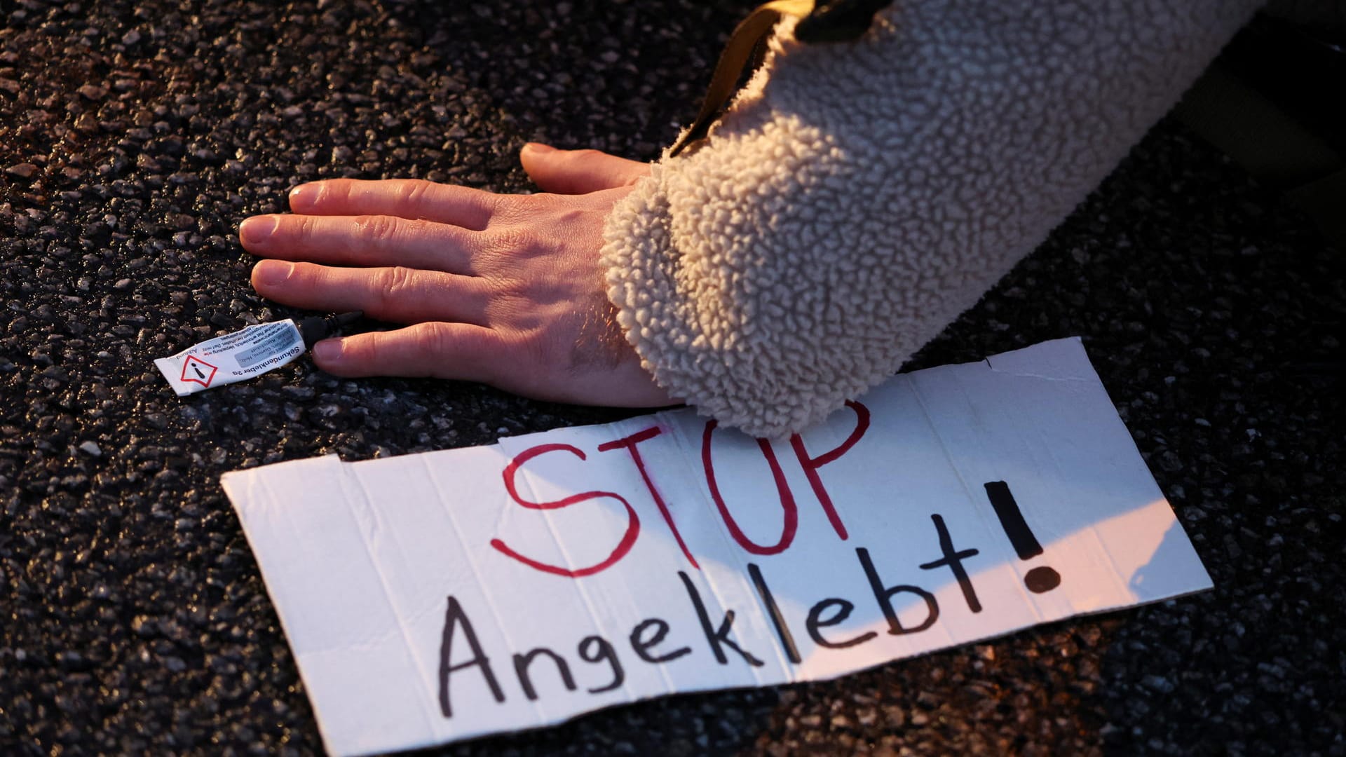 "Stop Angeklebt" steht auf einem Zettel: Die Polizei muss immer wieder Lösungsmittel einsetzen, um festgeklebte Aktivisten von den Straßen zu kriegen.