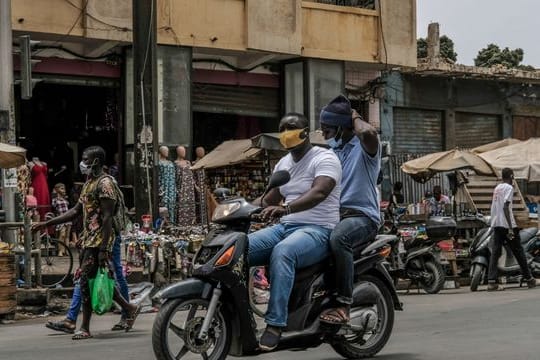 Mit Schutzmaske unterwegs auf dem Motorroller in Dakar.