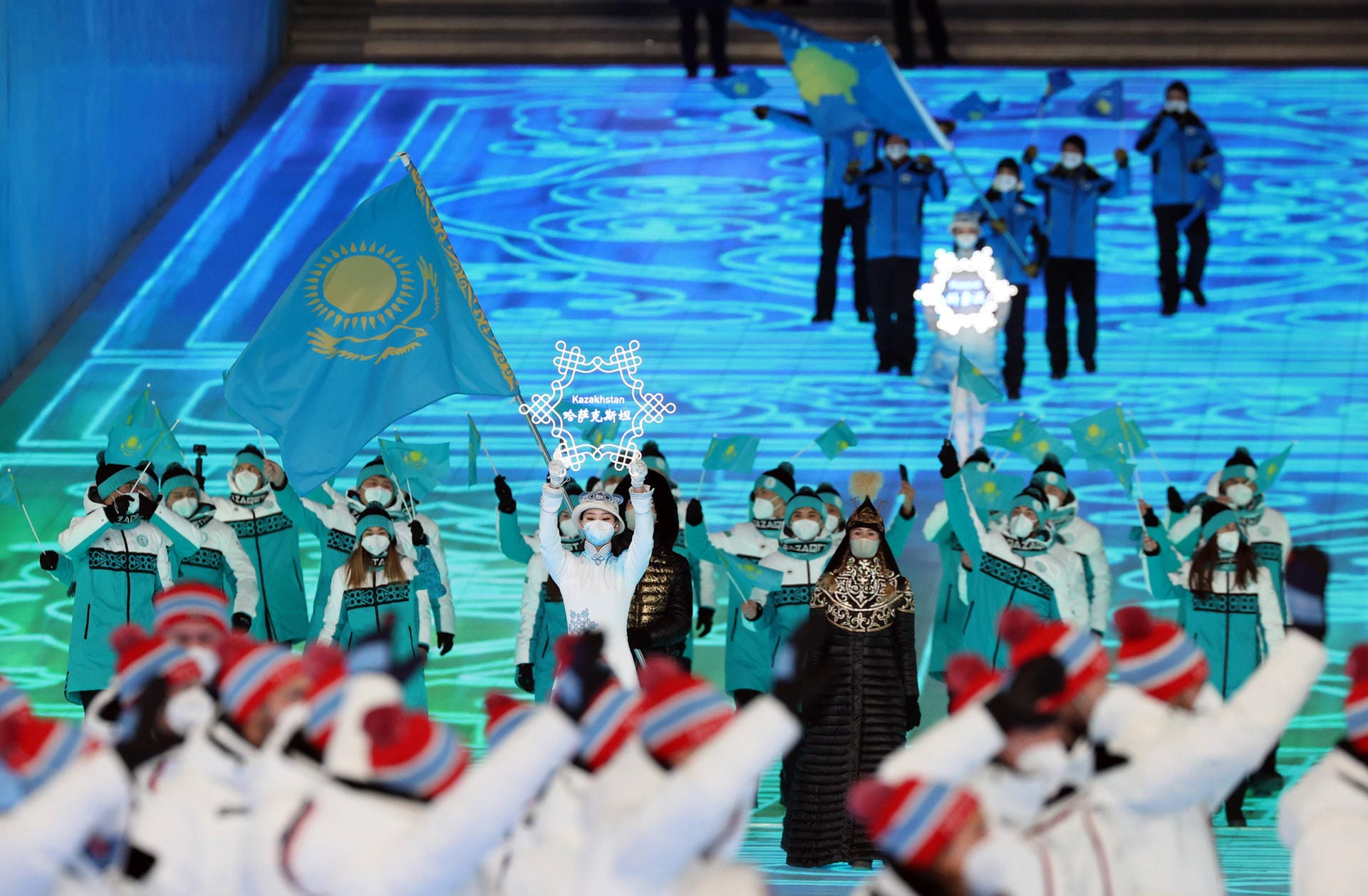 Die Sportler aus Kasachstan schwenken die Fahne: Das Land hatte sich ebenfalls auf diese Winterspiele beworben, im Jahr 2015 jedoch mit 40:44 Stimmen gegen China verloren.