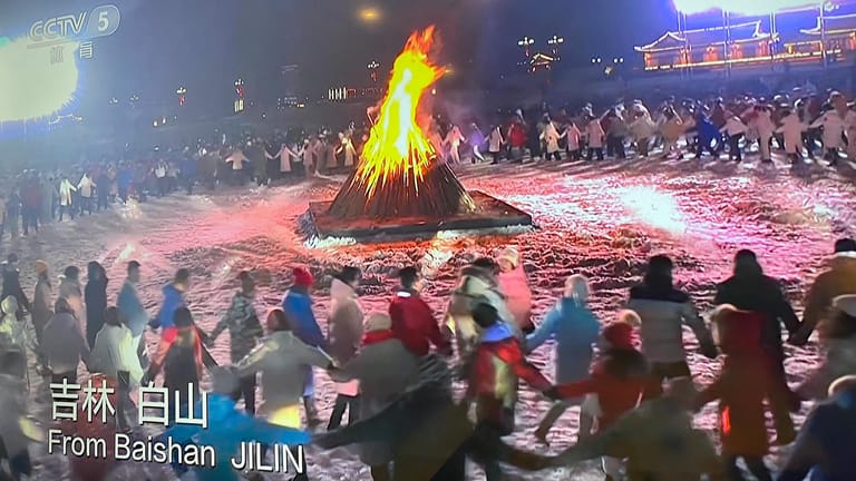 Vor der Eröffnung der Olympischen Spiele zeigt der Sender CCTV5 in Baishan Hunderte Menschen, die um ein Feuer tanzen.