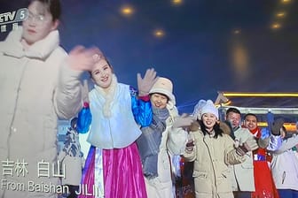 Auch ohne Maske: Im Programm des chinesischen Senders CCTV-5 grüßen vor der Eröffnungsfeier viele lachende Menschen in die Kamera.