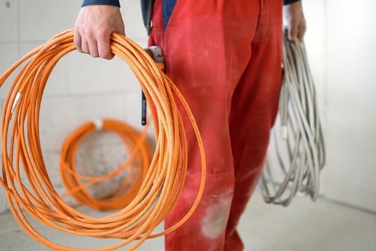 Ein Elektroniker-Lehrling steht auf einer Baustelle