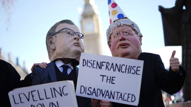 Zwei Demonstranten in Westminster haben sich als Minister Michael Gove und Premier Boris Johnson verkleidet - letzterer mit Partyhütchen.