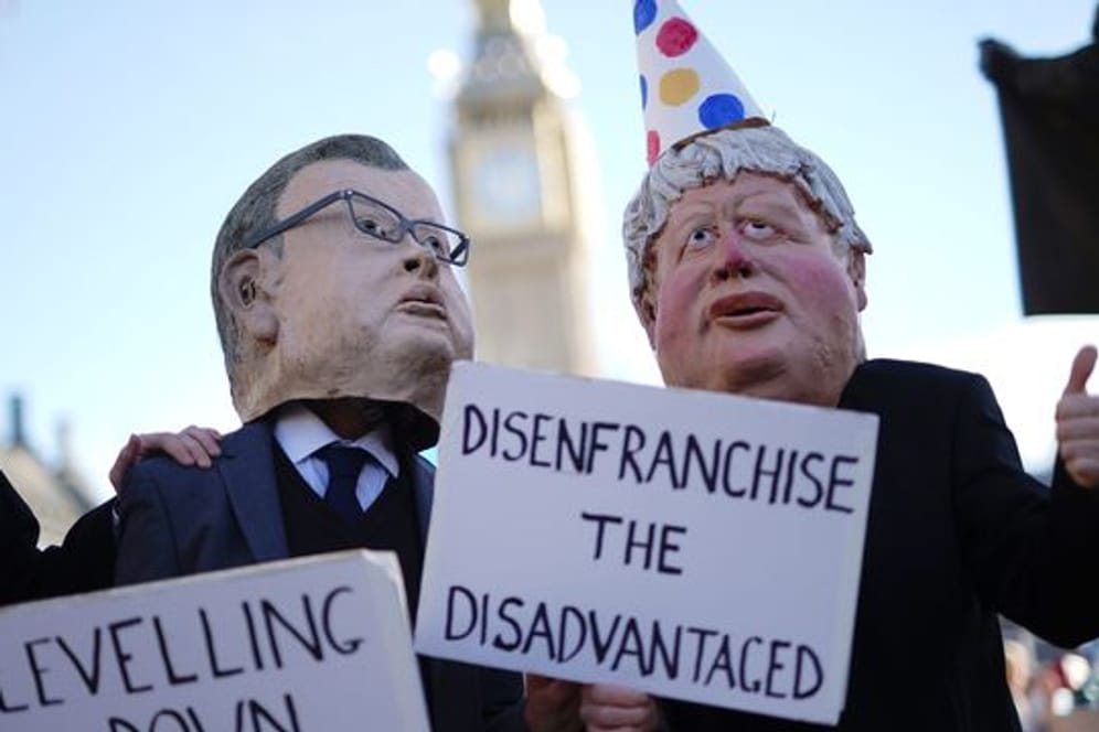 Zwei Demonstranten in Westminster haben sich als Minister Michael Gove und Premier Boris Johnson verkleidet - letzterer mit Partyhütchen.