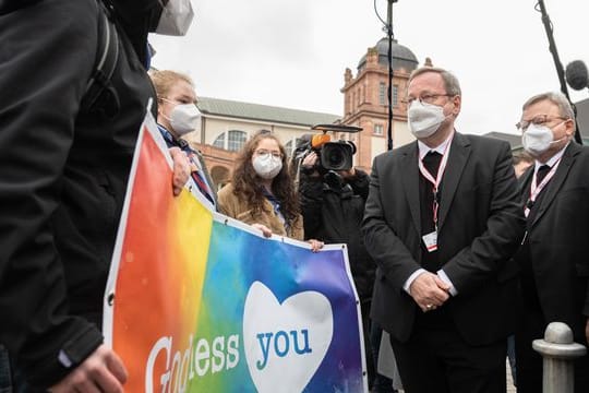 Der Vorsitzende der Deutschen Bischofskonferenz, Georg Bätzing, spricht vor der Synodalversammlung in Frankfurt mit Demonstranten, die eine vielfältigere Kirche fordern.