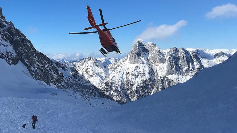 Ein Rettungshubschrauber fliegt über ein Lawinenfeld in den Berchtesgadener Alpen: In den letzten Tagen sind zehn Menschen durch Lawinen ums Leben gekommen.